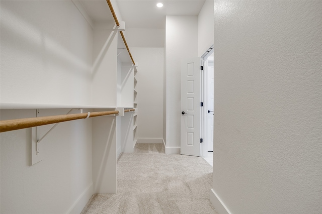 spacious closet featuring light colored carpet