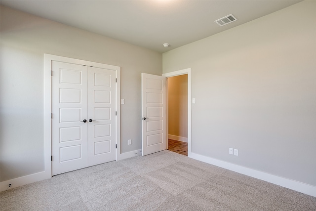 unfurnished bedroom featuring light carpet and a closet