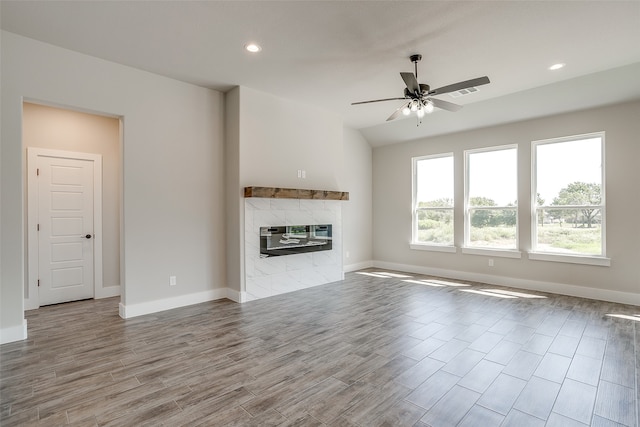 unfurnished living room with ceiling fan, light hardwood / wood-style floors, and a tile fireplace