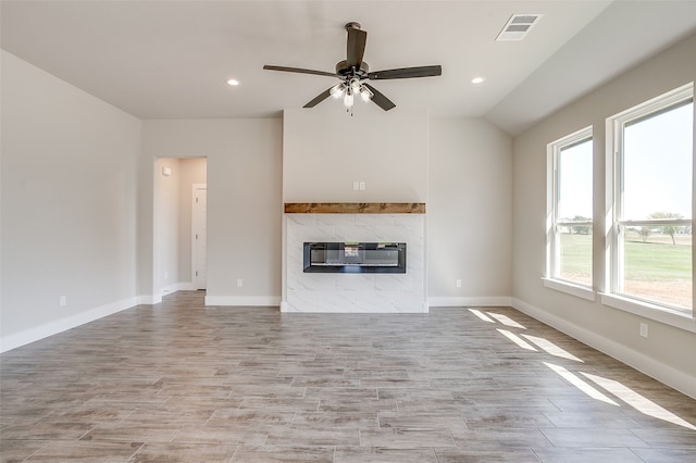 unfurnished living room with light hardwood / wood-style flooring, a wealth of natural light, ceiling fan, and a fireplace