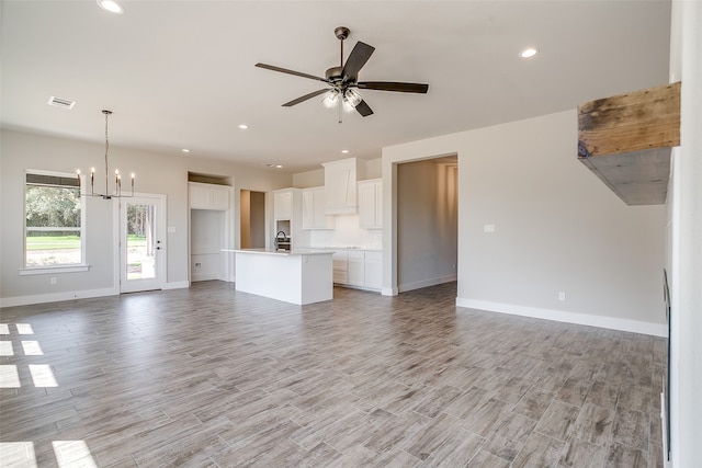 unfurnished living room featuring ceiling fan with notable chandelier, light wood-type flooring, and sink