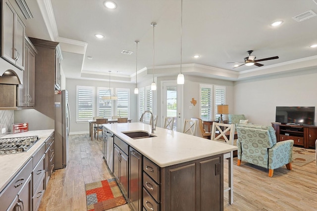 kitchen featuring pendant lighting, sink, stainless steel appliances, and a raised ceiling