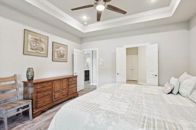 bedroom with ceiling fan, ornamental molding, a raised ceiling, and light wood-type flooring