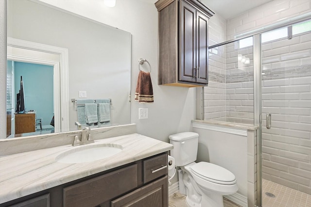 bathroom featuring vanity, toilet, and a shower with door