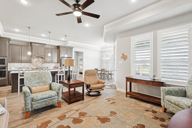 living room with crown molding, ceiling fan, and light hardwood / wood-style flooring