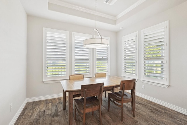 dining space with a raised ceiling, ornamental molding, plenty of natural light, and dark hardwood / wood-style flooring