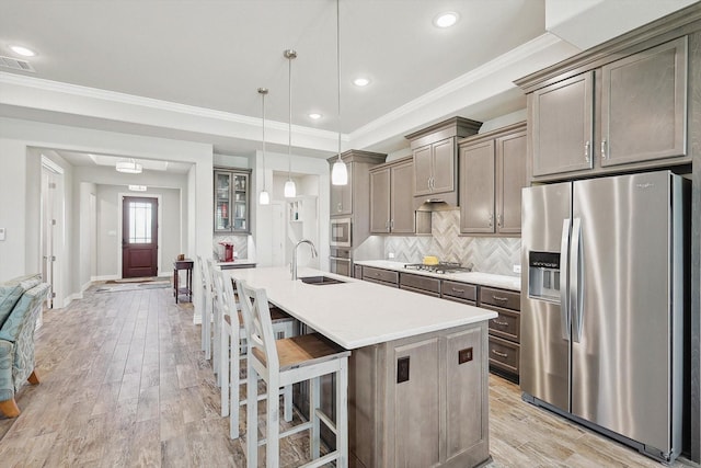 kitchen featuring sink, a kitchen breakfast bar, an island with sink, pendant lighting, and stainless steel appliances