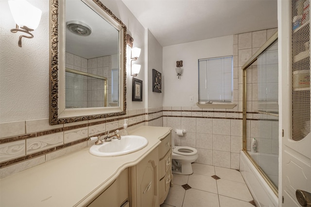 1457 Riverside Dr, West Tawakoni, TX 75474 - full bath featuring tile patterned floors, tile walls, toilet, vanity, and shower / bath combination with glass door