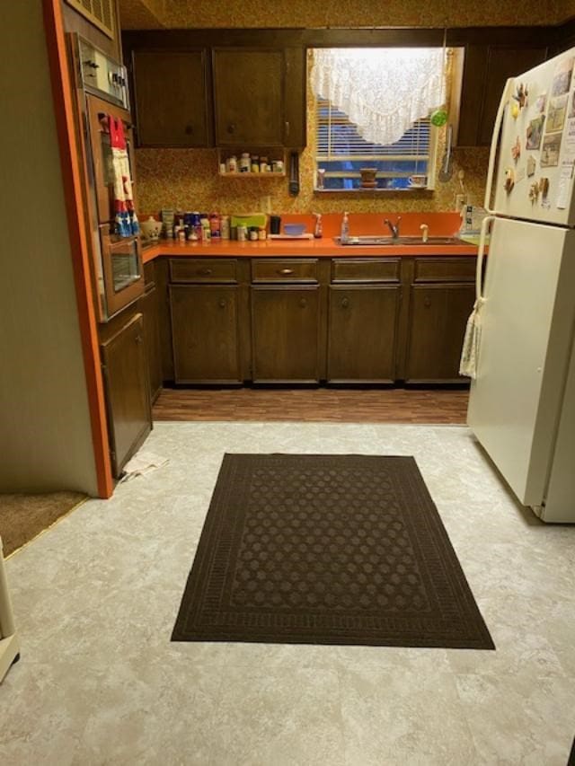 kitchen with sink, white refrigerator, and wall oven