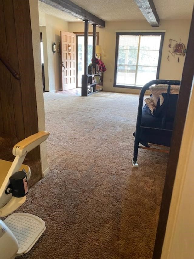 interior space with a textured ceiling, beam ceiling, and carpet flooring