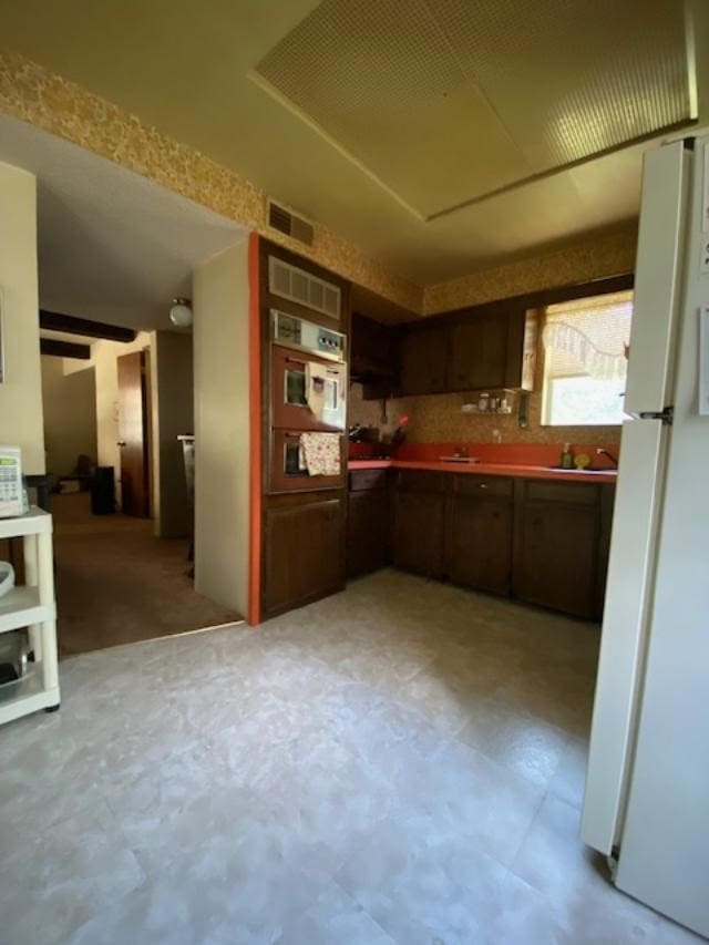 kitchen featuring dark brown cabinetry, oven, and white refrigerator