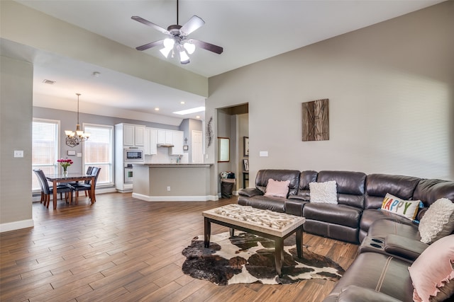 living room featuring ceiling fan with notable chandelier and hardwood / wood-style floors