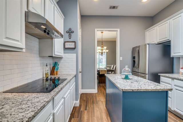 kitchen with a kitchen island, light hardwood / wood-style floors, wall chimney exhaust hood, decorative backsplash, and stainless steel fridge