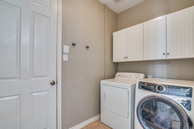 laundry area featuring washer and clothes dryer, cabinets, and light tile patterned floors