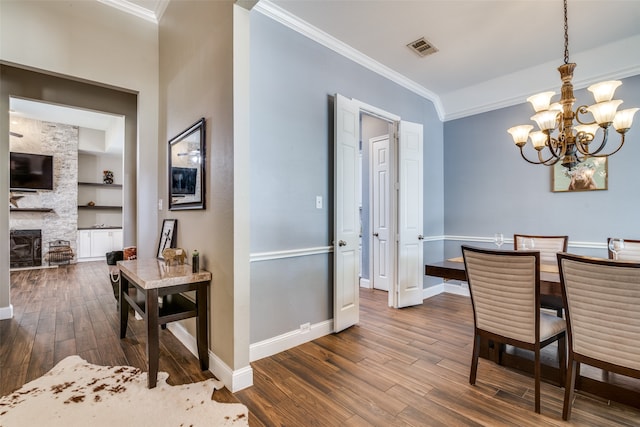 dining area with built in features, a fireplace, dark hardwood / wood-style floors, and a notable chandelier