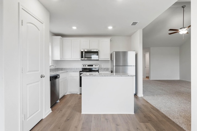 kitchen with a center island, light carpet, white cabinets, sink, and appliances with stainless steel finishes