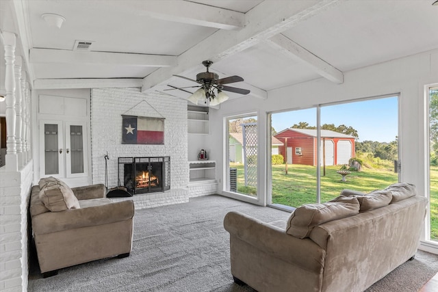 carpeted living room with ceiling fan, beamed ceiling, and a brick fireplace