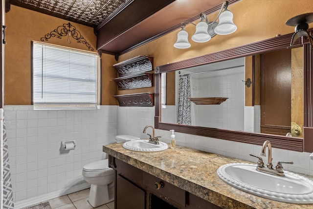 bathroom with toilet, vanity, tile patterned floors, and tile walls