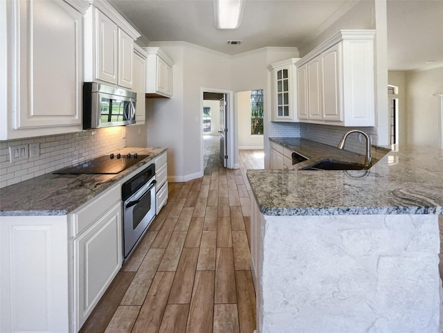 kitchen featuring white cabinets, stainless steel appliances, sink, ornamental molding, and light wood-type flooring