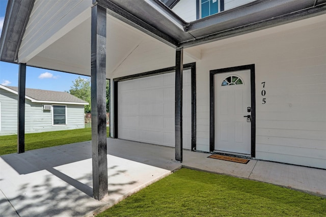 view of exterior entry featuring a garage and a yard