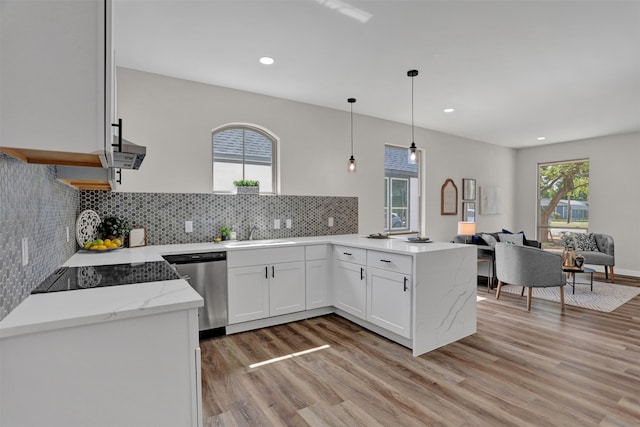 kitchen featuring white cabinetry, decorative light fixtures, light wood-type flooring, stainless steel dishwasher, and sink