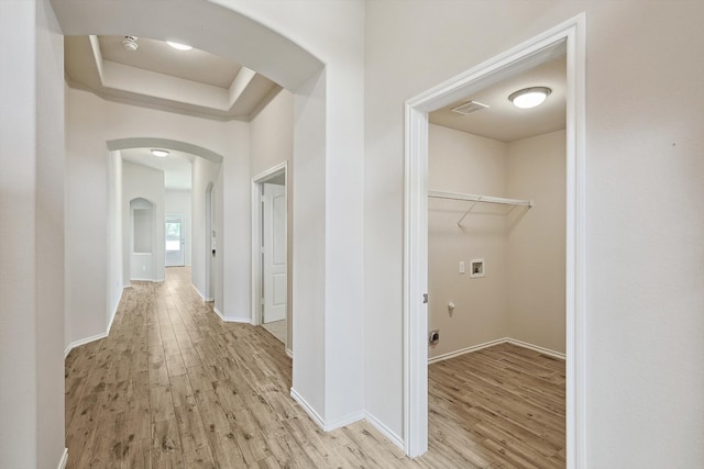 corridor featuring a tray ceiling and light hardwood / wood-style flooring