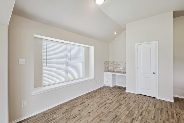 interior space featuring light hardwood / wood-style flooring, built in desk, and vaulted ceiling