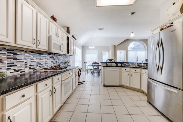 kitchen featuring appliances with stainless steel finishes, white cabinets, decorative light fixtures, decorative backsplash, and lofted ceiling