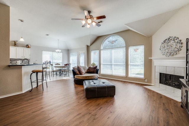1514 Murphy Dr, Rockwall, TX 75087 - living room with a tiled fireplace, ceiling fan with notable chandelier, lofted ceiling, and wood finished floors
