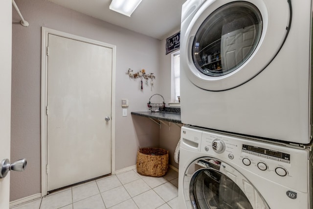 washroom featuring stacked washer and dryer and light tile patterned floors