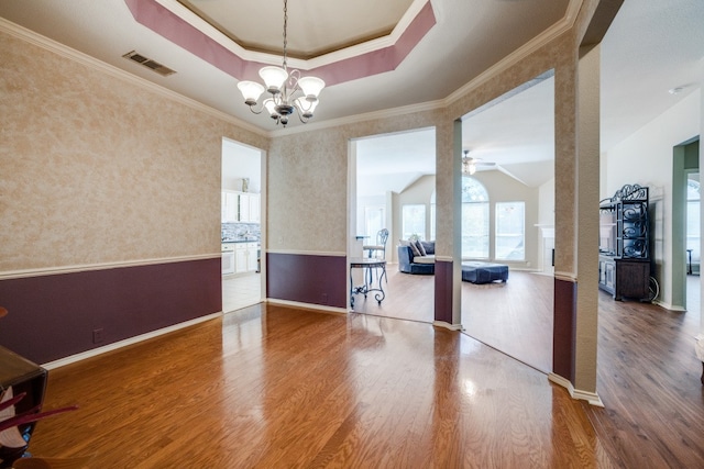 spare room with crown molding, a tray ceiling, hardwood / wood-style flooring, and ceiling fan with notable chandelier