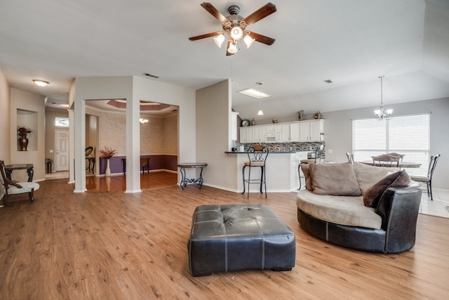 living room with light wood-type flooring and ceiling fan with notable chandelier