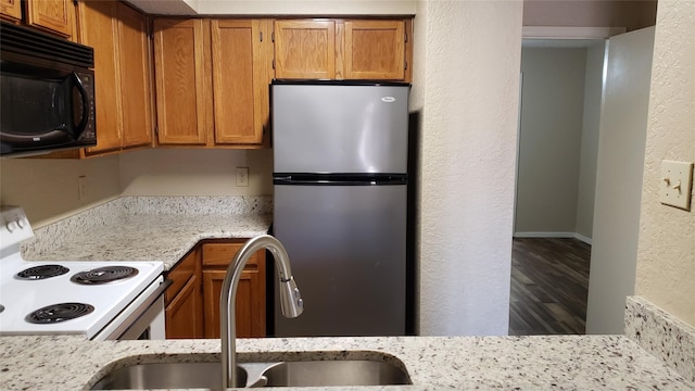 kitchen featuring white range with electric stovetop, light stone counters, hardwood / wood-style floors, and stainless steel fridge