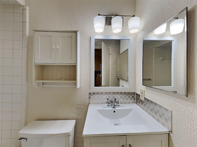 bathroom with vanity, toilet, and tasteful backsplash