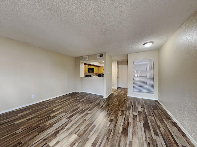 unfurnished living room featuring a textured ceiling and hardwood / wood-style floors