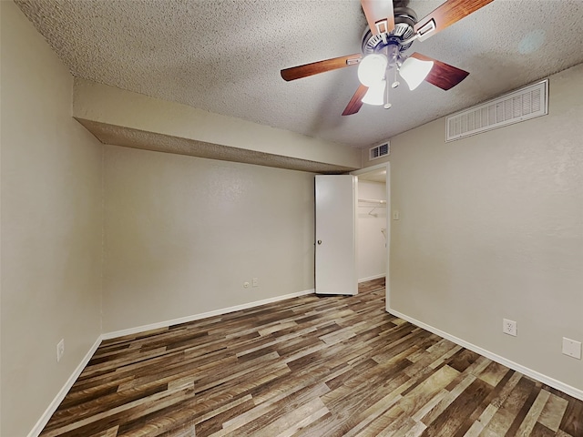 empty room with a textured ceiling, ceiling fan, and hardwood / wood-style floors