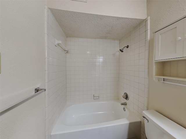 bathroom featuring tiled shower / bath combo, toilet, and a textured ceiling