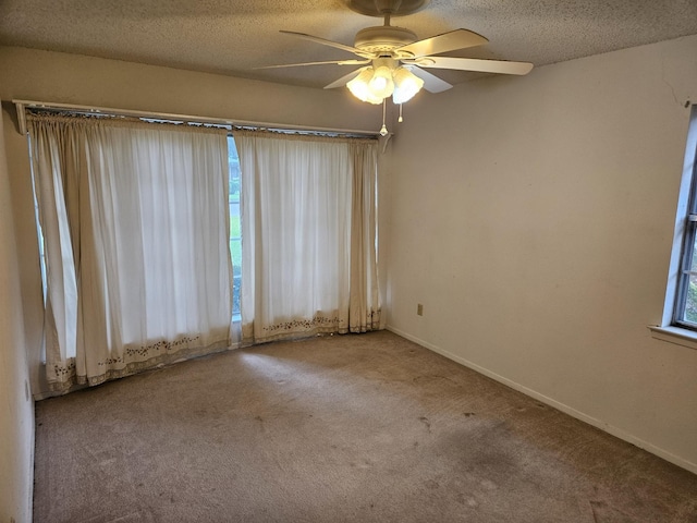 empty room with ceiling fan, carpet floors, a textured ceiling, and a wealth of natural light