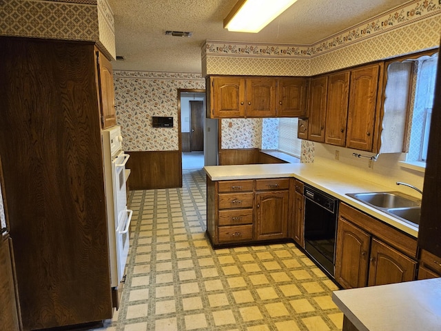 kitchen featuring sink, black dishwasher, kitchen peninsula, wood walls, and a textured ceiling