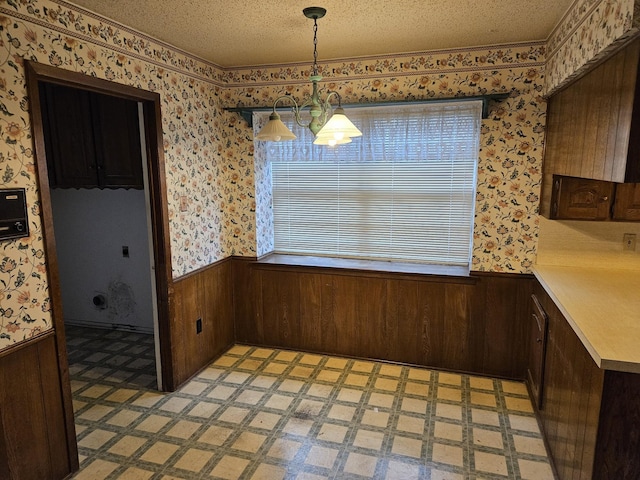 unfurnished dining area featuring a notable chandelier and a textured ceiling