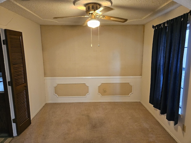 empty room featuring carpet flooring, ceiling fan, and a textured ceiling