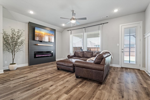 living room with a wealth of natural light, a large fireplace, hardwood / wood-style flooring, and ceiling fan