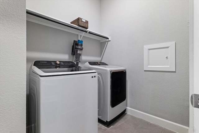 laundry area with washer and clothes dryer and light tile patterned flooring