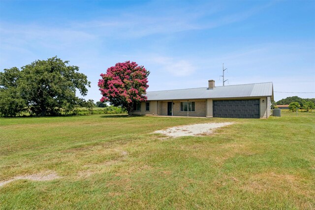 view of front of property with cooling unit, a garage, and a front lawn