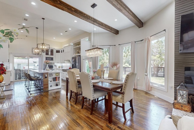 dining space featuring hardwood / wood-style flooring, beamed ceiling, and an inviting chandelier