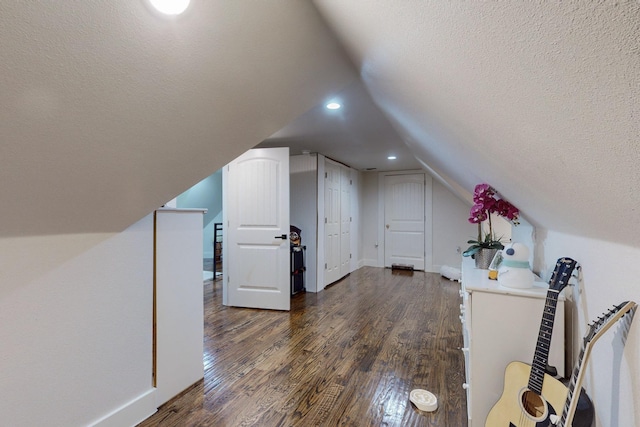 bonus room featuring dark hardwood / wood-style flooring, lofted ceiling, and a textured ceiling