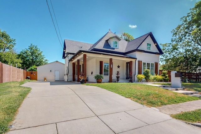 view of front of home with an outbuilding, a front lawn, a porch, and a garage