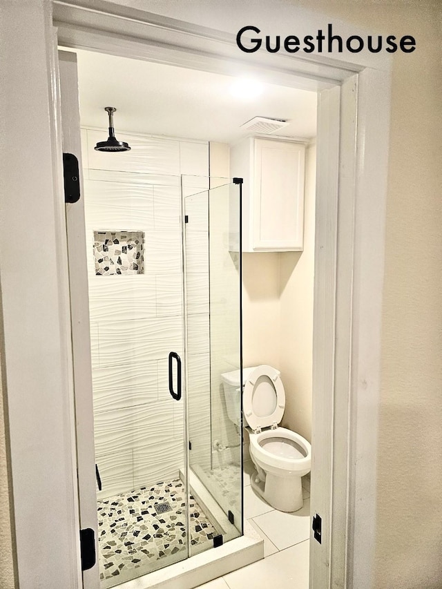 bathroom featuring tile patterned flooring, toilet, and walk in shower