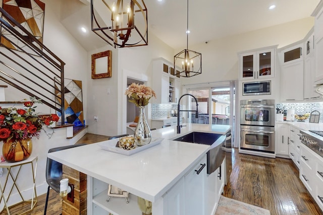 kitchen featuring appliances with stainless steel finishes, tasteful backsplash, white cabinetry, and a kitchen island with sink