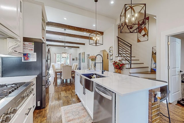 kitchen featuring white cabinetry, stainless steel dishwasher, and decorative light fixtures